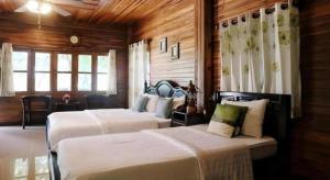 two beds in a room with wooden walls and windows at Ban Noi Resort Phrae in Phrae +165 photos
