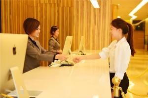 un gruppo di persone che stringono la mano a un tavolo di Echeng Hotel Qinzhou Bay Plaza East High-speed Railway Station a Qinzhou