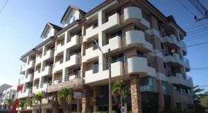 a large white building with palm trees in front of it at Butterfly Princess Hotel in Betong