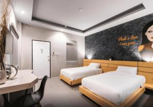 Una habitación de hotel con dos camas, un escritorio y una mesa. en Hide & Seek Resort Krabi, en Ao Nang Beach