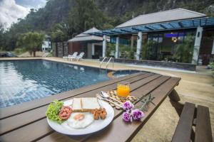 un piatto di cibo su un tavolo accanto a una piscina di Phuphayot Resort a Trang