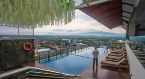 a man standing on top of a building with a swimming pool at Java Lotus Hotel Jember in Jember