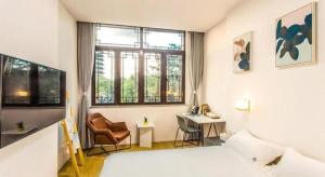 a bedroom with a bed and a chair and a window at Together-Venue Fawn Hostel Suzhou in Suzhou