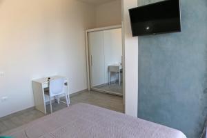 una camera da letto con scrivania e TV a parete di B&B Mimì a Castelsardo