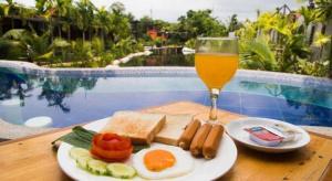 a plate of food and a glass of beer on a table at Panwana Resort in Rayong