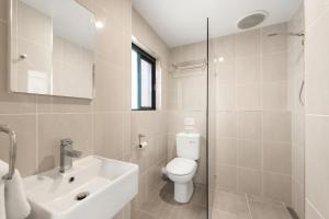 a white bathroom with a toilet and a sink at Atlantis 6 - 70 Lawson Street in Byron Bay +4 photos