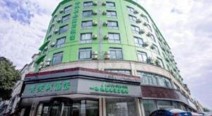 a tall green building with a sign on it at Vatica Hangzhou Linan Qianwang Street Hotel in Hangzhou
