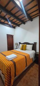 a bedroom with a large bed with yellow and white pillows at Casa Santiago Son 2 in Antigua Guatemala