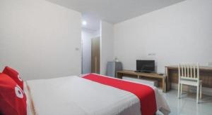 a bedroom with a bed and a desk and a television at Super OYO 662 Malee Bunga Hotel in Si Racha