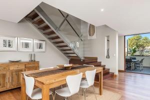 a dining room with a wooden table and white chairs at Casablanca - 2 - 21-25 Fletcher Street in Byron Bay