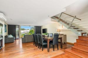 a dining room with a table and chairs and a staircase at A Seventh Heaven - 6 21- 25 Fletcher Street in Byron Bay
