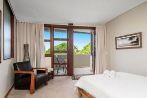 a bedroom with a bed and a chair and a window at A Seventh Heaven - 6 21- 25 Fletcher Street in Byron Bay
