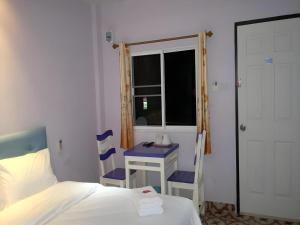 a bedroom with a bed and a table and a window at Wattana Hill Resort in Pattaya Central