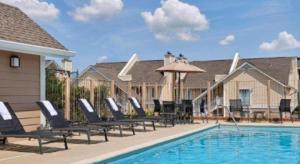 アナーバーにあるSonesta ES Suites Ann Arborの家の隣に椅子とパラソル付きのプールがあります。