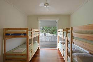 a room with three bunk beds and a door to a porch at Lantana Beach House - 77 Butler Street in Byron Bay