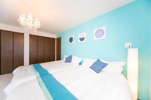 Un dormitorio con una gran cama blanca con paredes azules. en Ａｗａｊｉ Ｓｅａｓｉｄｅ Ｒｅｓｏｒｔ ｉｎ Ｉｋｕｈａ - Vacation STAY 77513v, en Awaji
