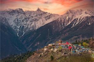 a village on a hill with mountains in the background at Echor - The Alpine Crest in Kalpa
