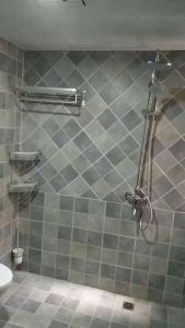 a shower in a bathroom with a tiled wall at Xiaowo SmileNest Downtown Scenic Spot Ticket Service Close to Tianmen Mountain Scenic Area Ideal for Couples, Families and Group Bookings in Zhangjiajie +7 photos