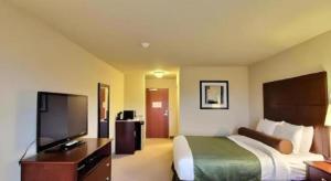 a hotel room with a bed and a flat screen tv at AmericInn by Wyndham Oshkosh in Oshkosh
