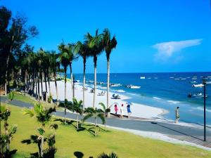 people walking on a beach with palm trees and the ocean at Excemon Beach Hotel Beihai in Beihai
