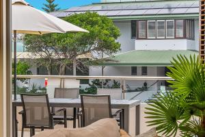 a balcony with a table and chairs and a building at Pipi's On The Beach 1 - 2 Fletcher Street in Byron Bay