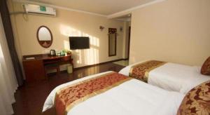 a hotel room with two beds and a desk at GreenTree Inn Linyi Feixian Jianshe Road Express Hotel in Linyi