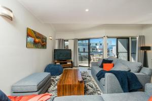 Una sala de estar con un sofá y un televisor. en Absolute Solace - 2 - 8 Lawson Street, en Byron Bay