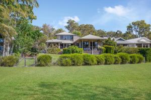 a house with a fence in front of a yard at Lakeside Bliss in Dunbogan