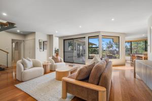 a living room with a couch and chairs and windows at Lakeside Bliss in Dunbogan