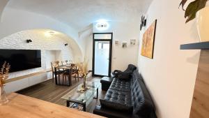 a living room with a black leather couch and a table at Apartments KrAnJ - Family apartment Jurček in Kranj