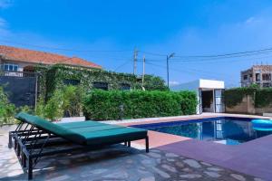 a swimming pool with a bench next to a house at Modern pool house in Kampala in Kampala