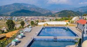 un complexe avec une piscine et une ville dans l'établissement Capital O 653 Seven Lakes Resort, à Pokhara