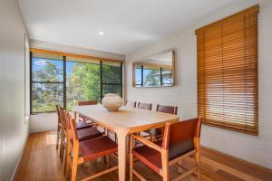 a dining room with a wooden table and chairs at Lakeside Bliss in Dunbogan