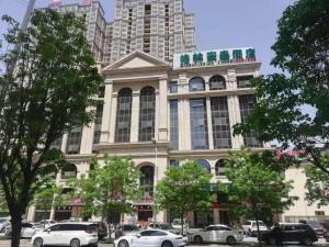 Un gran edificio con coches aparcados delante. en GreenTree Inn Luoyang Train Station Zhuangyuanhong Road Hotel, en Luoyang