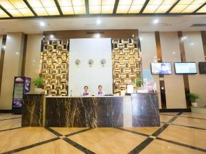 two people standing at a counter in a lobby at GreenTree Alliance Hotel Yongzhou Lingling Zhong Road in Guzhuting