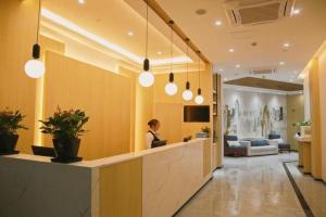 a woman sitting at a reception desk in a lobby at GreenTree Inn Nanjing Baijiahu in Nanjing