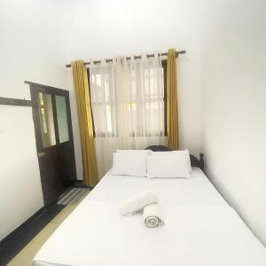 a bedroom with a bed with white sheets and a window at Villa Senu in Ambalangoda +66 photos