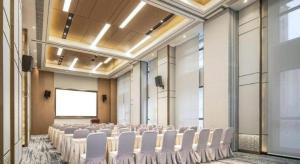 a room with rows of white chairs in a room at Metropolo Hotel Yining Development Zone Hanma Building in Kipekyüzi