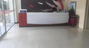 a counter in a building with a man standing at a counter at Thank Inn Hotel Hebei Langfang Xianghe County Guidu Furniture Center in Jinxinzhuang