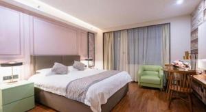 a bedroom with a large bed and a green chair at GEM Hotel Ningbo Jiangbei District Hongtang Haide Square in Kao-ch'iao +177 photos