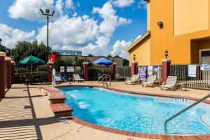 a swimming pool at a hotel with chairs and umbrellas at Comfort Suites Westchase Houston Energy Corridor in Houston