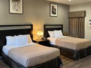 a hotel room with two beds and a lamp at Rodeway Inn El Cajon - San Diego East in El Cajon