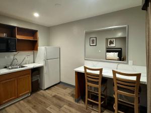 a kitchen with a white refrigerator and two chairs at Rodeway Inn El Cajon - San Diego East in El Cajon