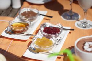 a wooden table topped with bowls of food and spoons at Valis Resort Hotel in Volos
