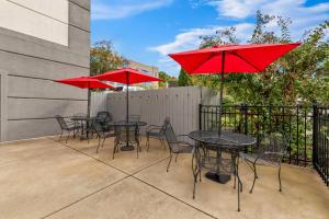 a patio with tables and chairs with red umbrellas at Brentwood Suites Nashville, an Ascend Collection Hotel in Brentwood