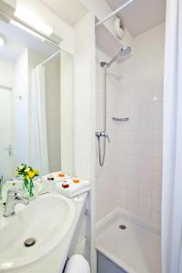 La salle de bains blanche est pourvue d'un lavabo et d'une douche. dans l'établissement Séjours & Affaires Paris Ivry, à Ivry-sur-Seine