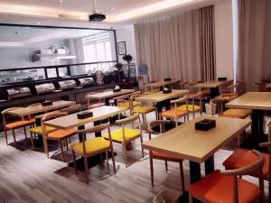 a restaurant with wooden tables and yellow chairs at GreenTree Inn Heze Railway Station Hotel in Heze
