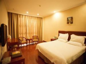 a hotel room with a bed and a table at GreenTree Inn Heze Railway Station Hotel in Heze