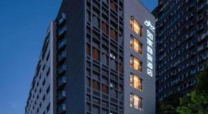 上海市にあるHome Inns Plus Shanghai Xujiahui Branchの時計付きの高層ビル