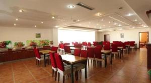 a restaurant with red chairs and tables in a room at GreenTree Inn Tianjin Wuqing Distric Bohai Market in Tianjin